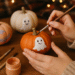 Hands painting a cute ghost on a pumpkin for an easy Halloween DIY craft, with cozy warm lights in the background