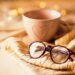 Cozy September journaling scene with a warm mug, open journal, knitted sweater, and glasses on a wooden table, illuminated by soft golden lights.