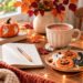 cozy halloween bucket list with a ghost painted pumpkin, hot chocolate, journal, Halloween cookies, fairy lights and autumn decor on a cozy table